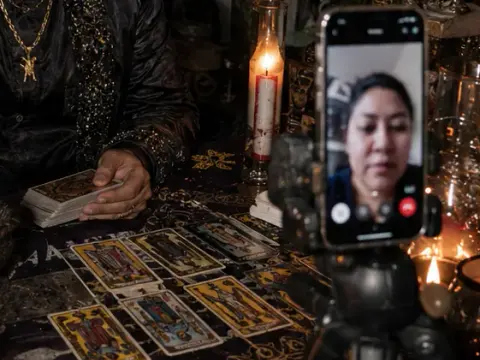 Cartas de tarot junto a un teléfono en videollamada